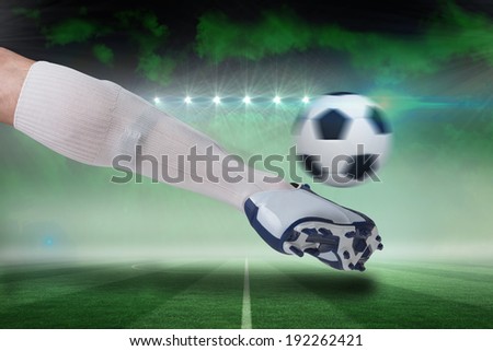 Composite image of close up of football player kicking ball against football pitch under green sky