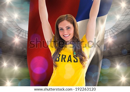 Pretty football fan in brasil t-shirt holding chile flag against large football stadium with lights