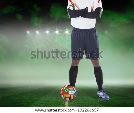 Composite image of goalkeeper standing with international ball against football pitch under green sky