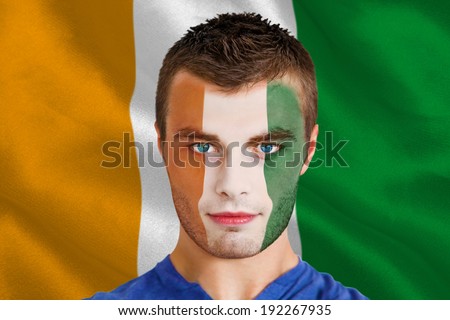 Composite image of serious young football fan in face paint against ivory coast national flag