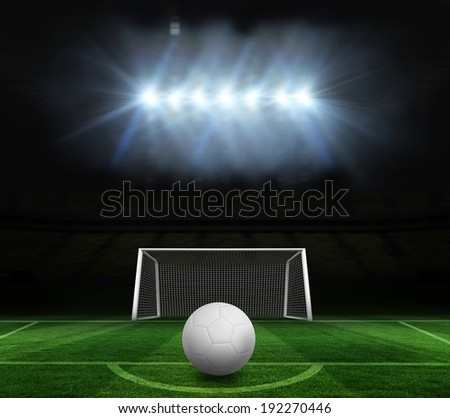 Digitally generated white leather football against football pitch and goal under spotlights