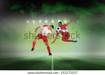 Football players tackling for the ball against football pitch under green sky