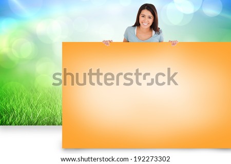 Composite image of pretty brunette showing orange card