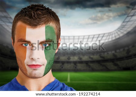 Composite image of ivory coast football fan in face paint against large football stadium with lights