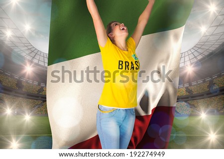 Excited football fan in brasil tshirt holding italy flag against large football stadium with lights