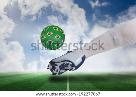 Composite image of close up of football player kicking brasil ball against football pitch under blue sky