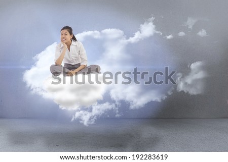 Businesswoman sitting cross legged thinking against clouds in a room