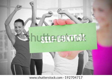 Fit blonde holding card saying self control against fitness class in gym