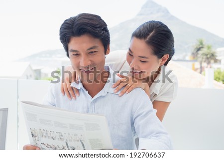 Couple reading a newspaper together outside on a balcony