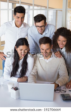 Casual smiling business team having a meeting using laptop in the office