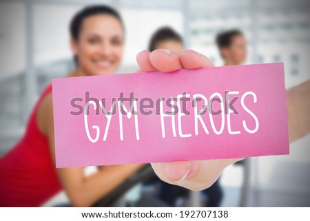 Woman holding pink card saying gym heroes against fitness class in gym