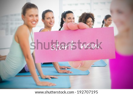 Fit blonde holding card saying start now against yoga class in gym
