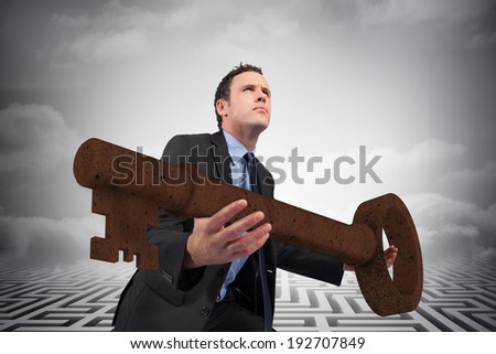 Businessman carrying large key with arms out against clouds over maze