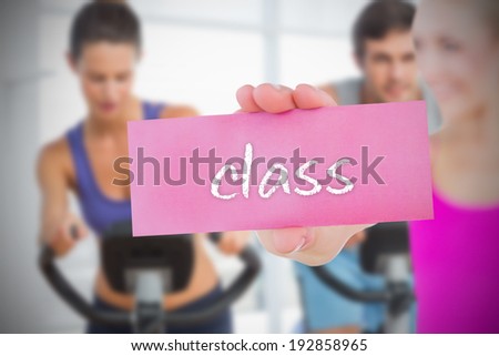Fit blonde holding card saying class against fitness class in gym