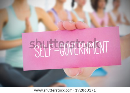 Woman holding pink card saying self government against yoga class in gym