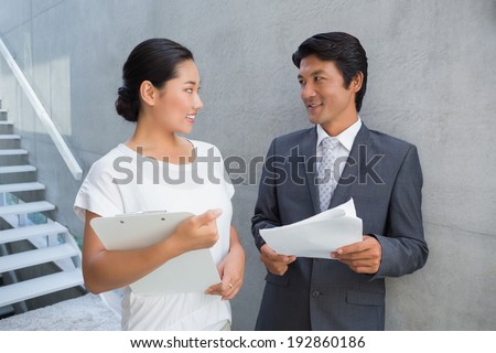 Estate agent showing lease to customer and smiling outside a house