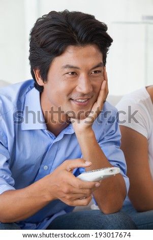 Happy man sitting on couch watching tv at home in the living room