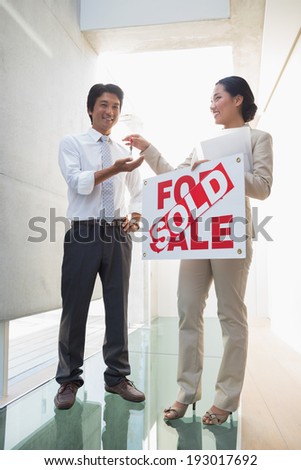 Estate agent giving keys to new home owner in the hallway