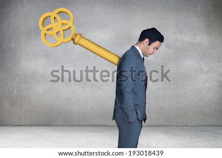 Composite image of wound up businessman with hands in pockets against grey room