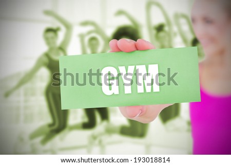 Fit blonde holding card saying gym against fitness class in gym