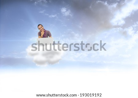 Thinking man sitting on floor using laptop and smiling against beautiful orange and blue sky