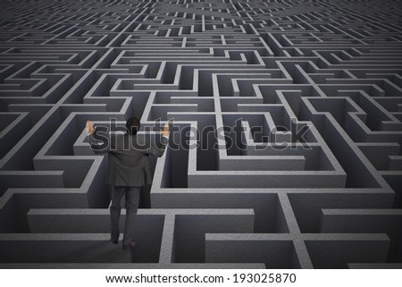Businessman posing with arms raised against difficult maze puzzle