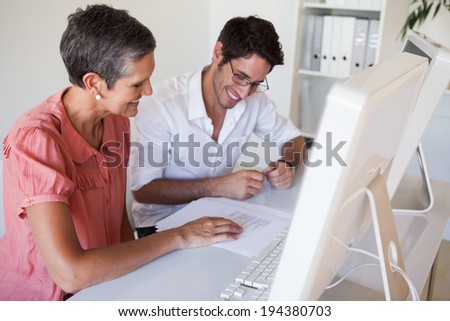 Casual business team working together at desk using computer in the office