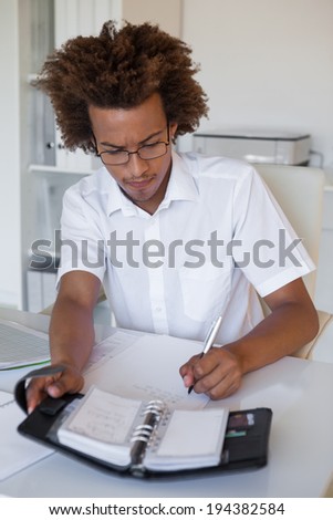 Casual young businessman organizing his schedule at his desk in his office