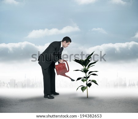 Businessman watering with red can against city on the horizon