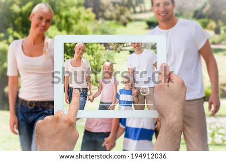 Hand holding tablet pc showing adorable family in the park