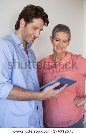 Casual smiling business team looking at tablet pc together in the office