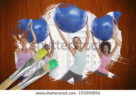 Composite image of fitness class at the gym against wooden oak table with paintbrushes