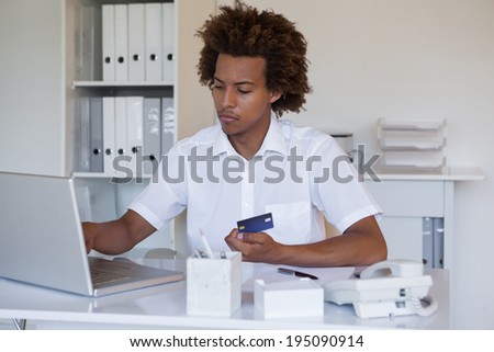 Relaxed casual businessman shopping online at his desk in his office