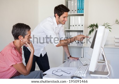 Casual business team working together at desk using computer in the office