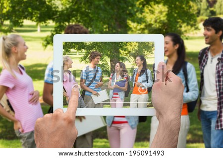 Hand holding tablet pc showing group of cheerful college friends in campus