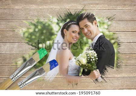 Composite image of newlyweds smiling at camera with paintbrush dipped in blue against wooden surface with planks