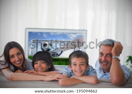 Family smiling at the camera with television