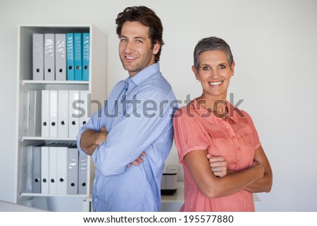 Casual smiling business team standing back to back in the office