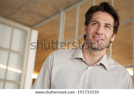 Casual businessman thinking and smiling in his office