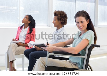 Attractive businesswoman in wheelchair smiling in the workplace in the office