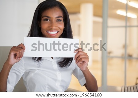 Pretty businesswoman showing white card at her desk in her office