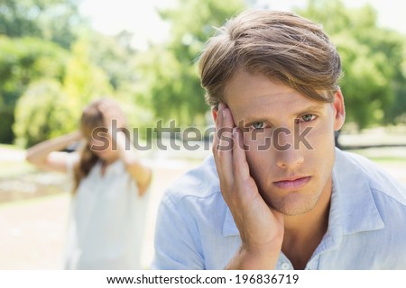 Upset man looking at camera after a fight with his girlfriend in the park on a sunny day