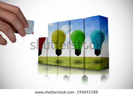 Hand building wall showing light bulbs floating over field