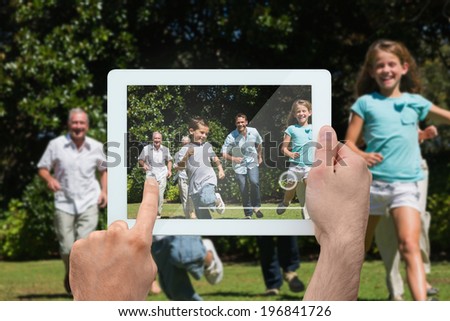 Hand holding tablet pc showing happy multi generation family racing towards camera