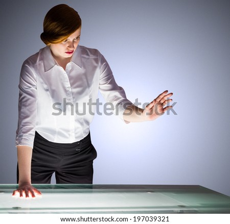 Redhead businesswoman standing and gesturing by a desk on shadow background