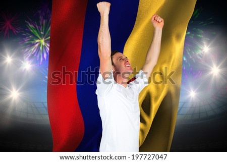 Cheering football fan in white against fireworks exploding over football stadium and colombia flag