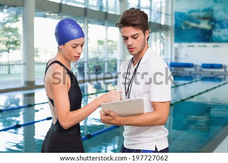 Swimmer discussing times with her coach by the pool at the leisure center