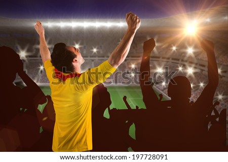 Cheering football fan in yellow jersey against large football stadium with lights