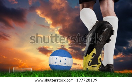 Composite image of football boot kicking honduras ball against green grass under dark blue and orange sky