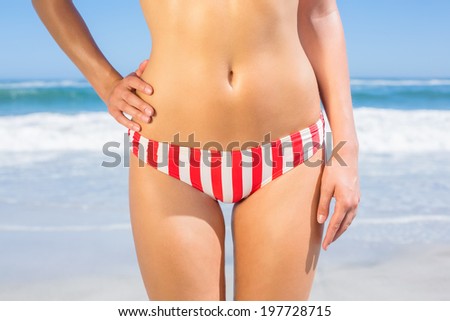 Mid section of fit woman in bikini on the beach on a sunny day